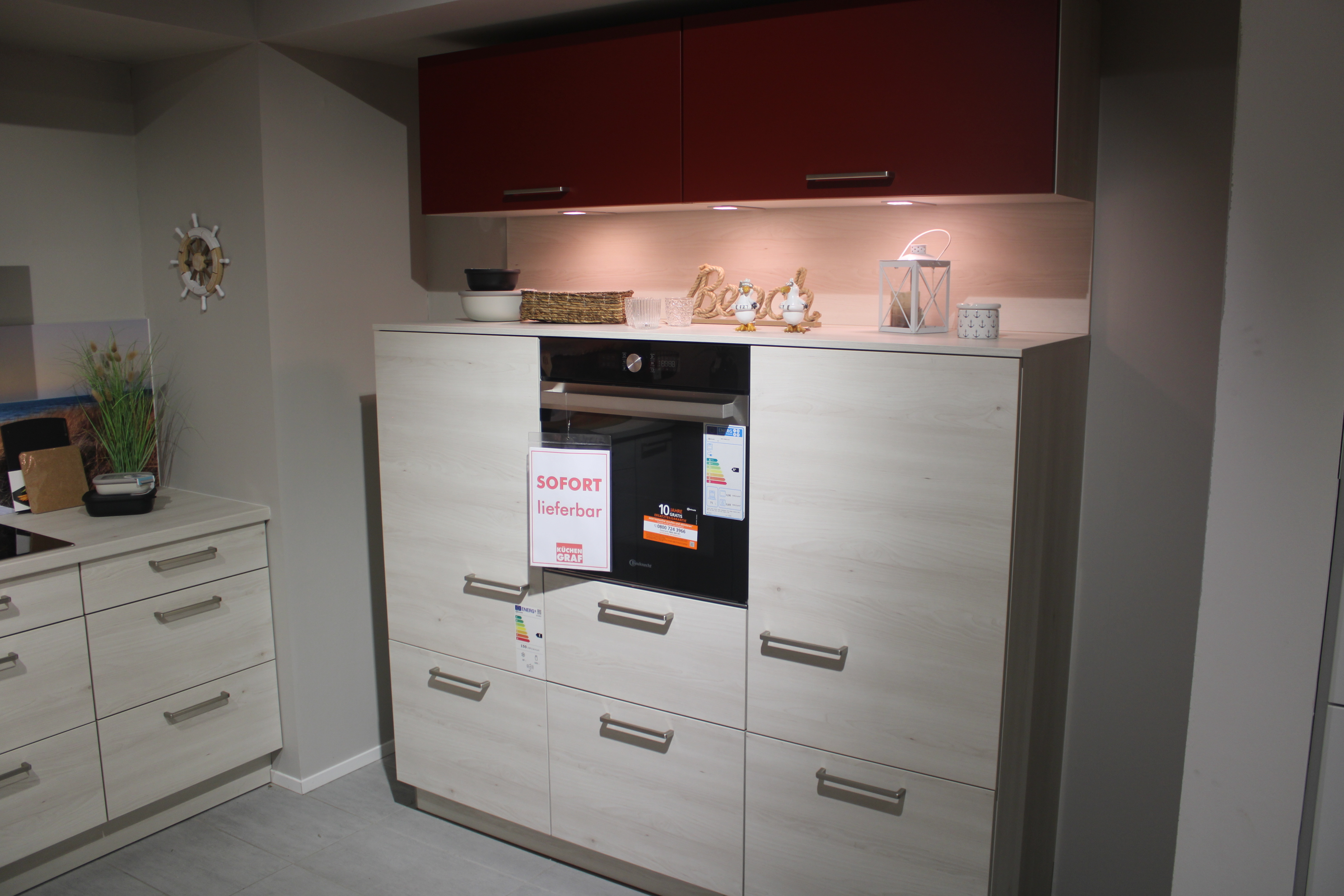 Musterküche, in Kuruna Birke und rot, Griffe Edelstahloptik - Nolte Manhattan